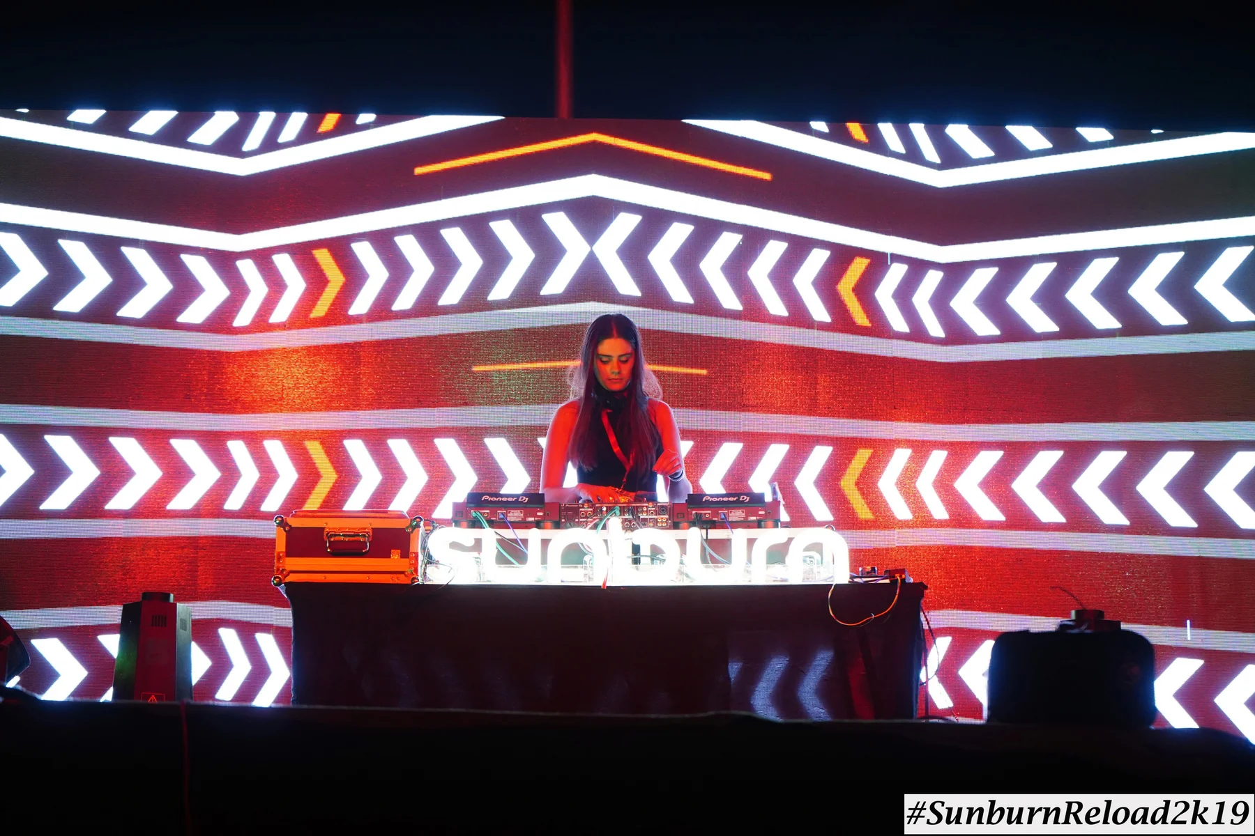 Mira Mira performing at a large event with an illuminated stage backdrop