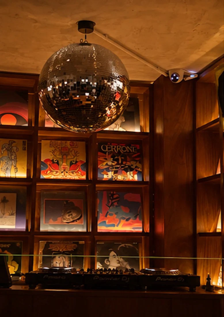 Warmly lit event space with DJ booth and mirrored disco ball